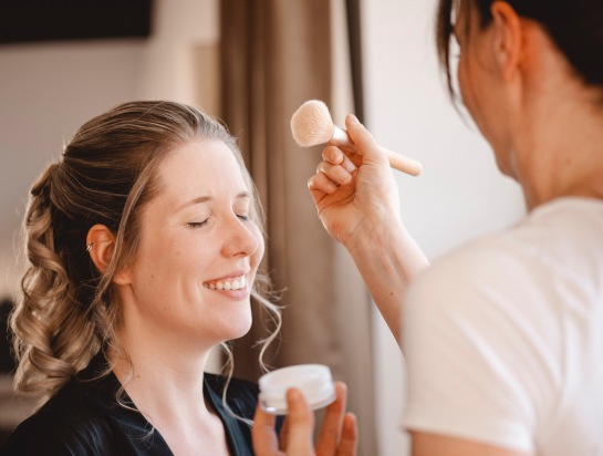 Braut beim Frisieren und Schminken am Fenster Hochzeitsreportage